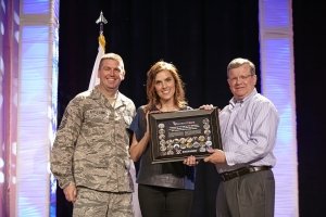 Chief Master Sgt. Sean Applegate and Director/CEO Tom Shull award Taya Kyle a POG plaque after her inspiring speech at the MSM/GM conference.