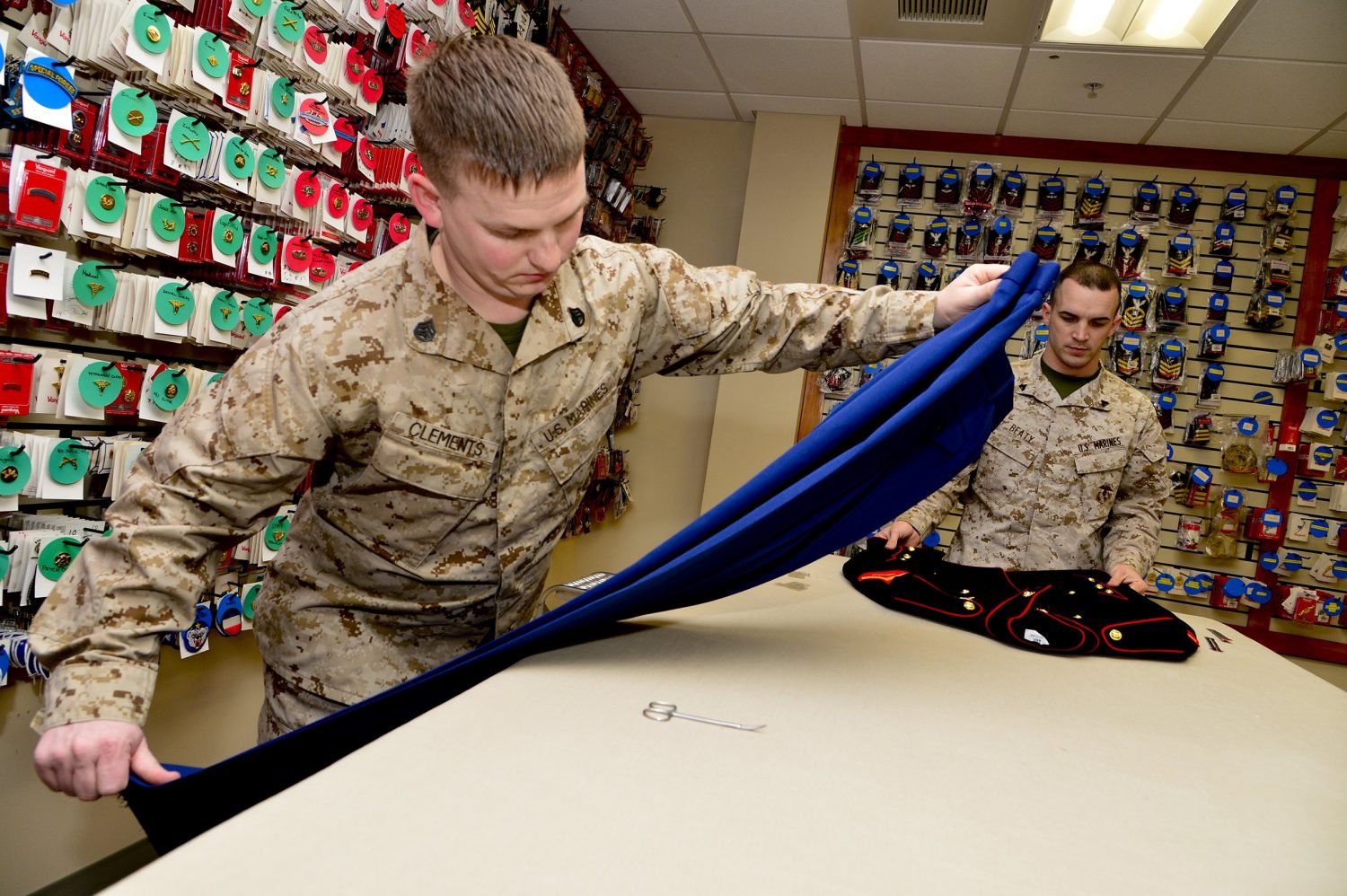 Staff Sgt. John Clements, left, and Corp. Landon Beaty, Air Force Mortuary Affairs Operations, assemble a dress blues uniform for a fallen Marine. (U.S. Air Force photo/David Tucker)