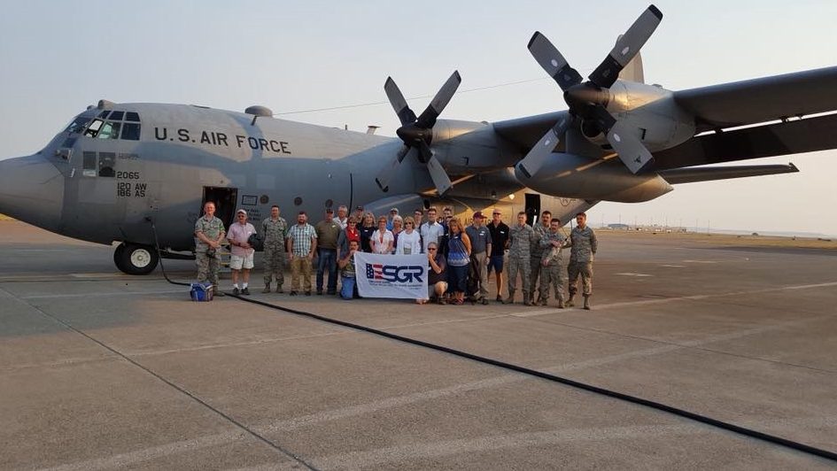 Wanda Cummins and 24 other "bosses" pose in front of the C-130 plane that took them on an excursion over Central Montana.