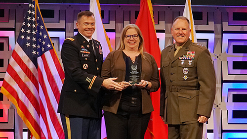 Col. Douglas Vallejo, deputy director, Logistics; and Morgan Meeks, vice president, Transportation Operations, accept the award from TRANSCOM Deputy Commander Marine Corps Lt. Gen. John Broadmeadow, right.