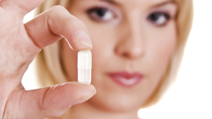 Woman holding up pill.