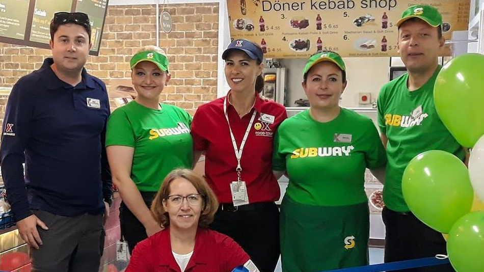 General Manager Lori Maggard, kneeling, poses with local residents who work for the Exchange's new Subway at Kosovo's Camp Bondsteel.