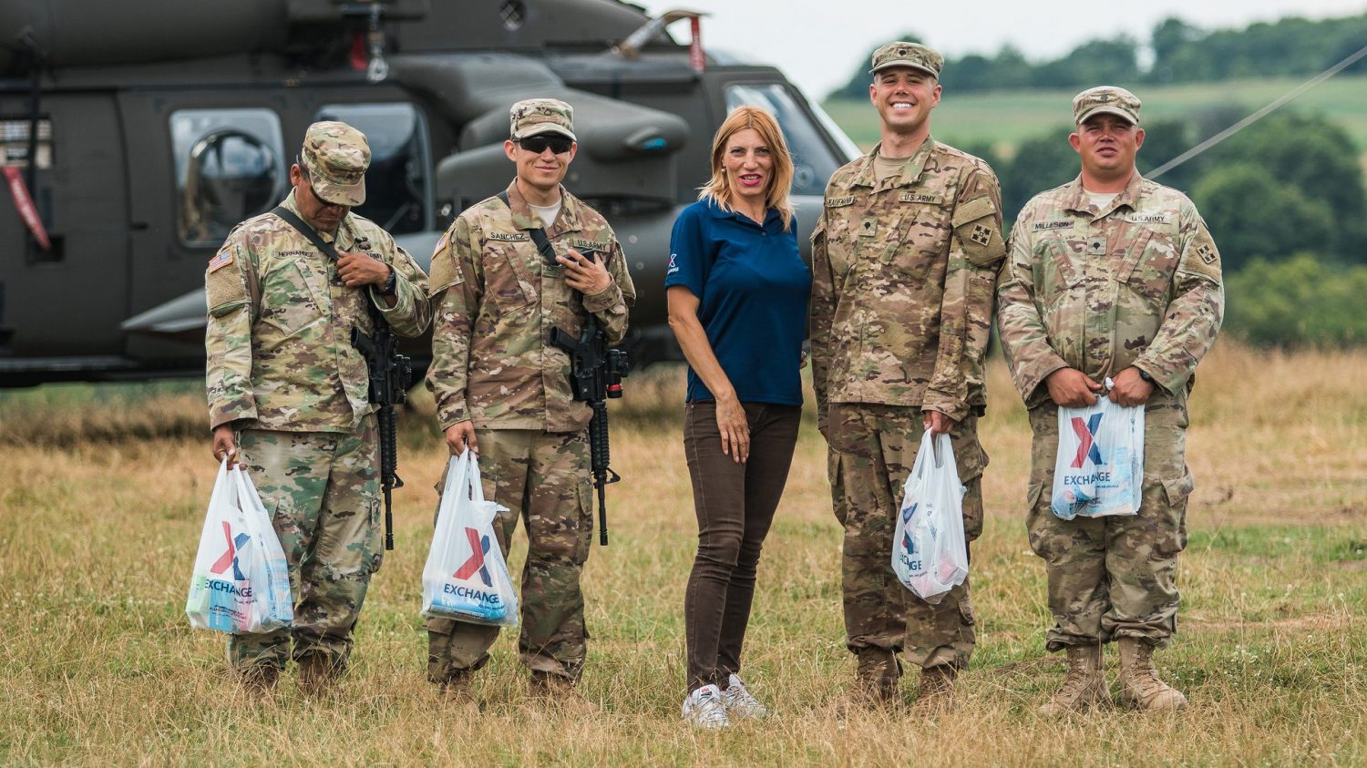 Associate standing with four Soldiers in a field beside a helicopter. Illustrates Exchange relevancy.