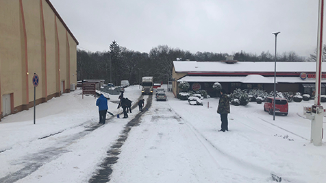 BAUMHOLDER, Germany - No amount of cold, wintery weather can freeze the spirit of family serving family! Associates from Baumholder's Military Clothing Store and Burger King clear a path for an Exchange trucker on the whopper of a snowy hill.