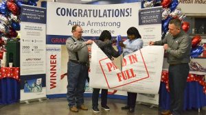 Exchange shopper Anita Armstrong, second from left, and General Manager Vanessa Rowland take scissors to Armstrong's MILITARY STAR bill, which the Exchange Credit Program paid in full during a sweepstakes. Joining are, far left, are Armstrong's husband, retired Tech Sgt. Michael Armstrong; and, far right, Exchange Vice President, Credit Operations, Tommy Ward.