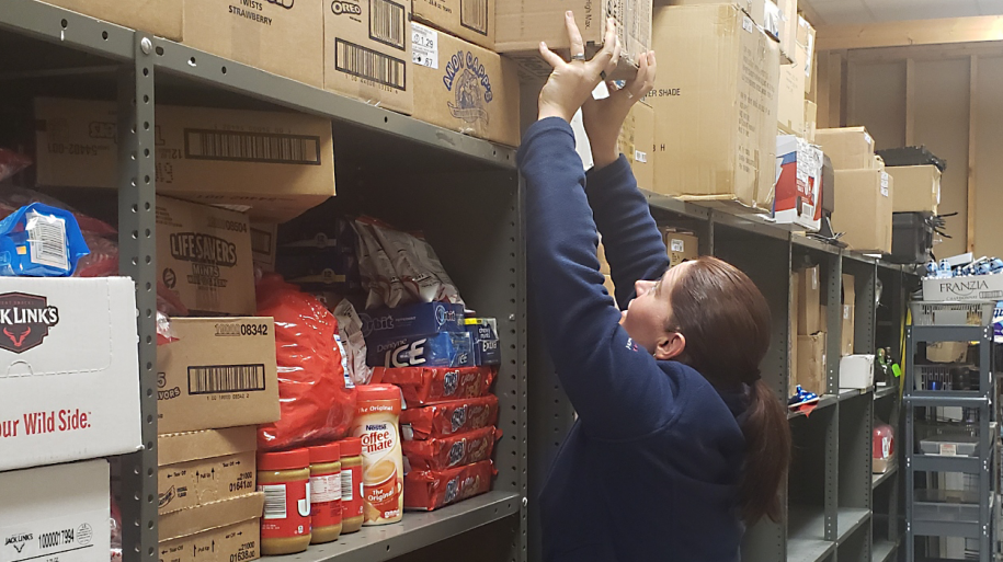 Store Manager Katie Oster moves products to a top shelf out of harm's way.