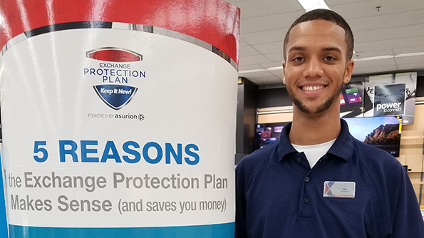 Associate beside an Exchange Protection Plan promotional sign.