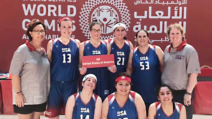 Fort Sam Houston Associate Jamie Holt, holding sign, joins her teammates at the Special Olympics World Games.