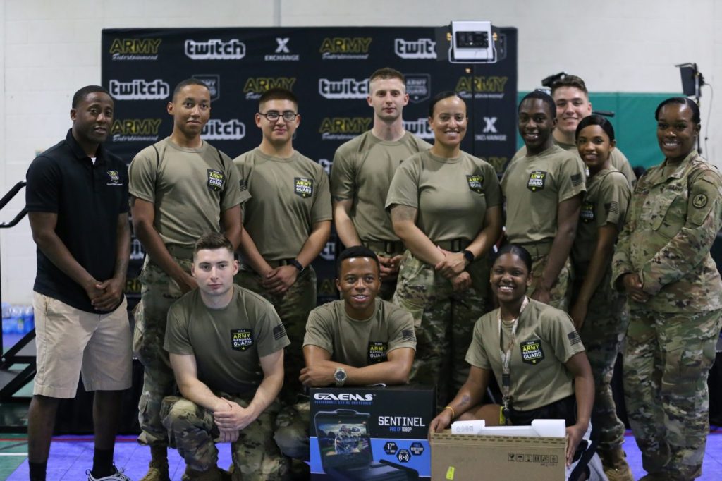 Texas National Guard Soldiers pose in two rows in front of an event banner