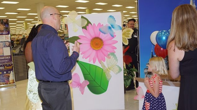 General Manager Mikel Hunter builds anticipation for little Annabelle Acosta as to what is inside the big box she is about to open.