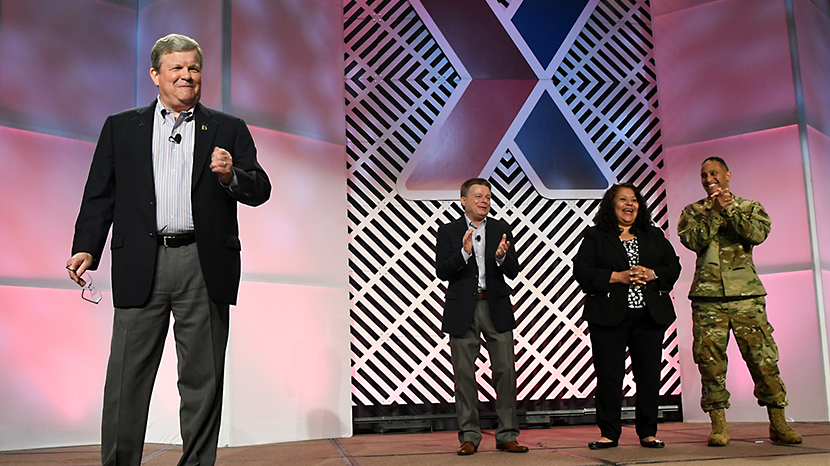 Exchange Director/CEO Tom Shull speaks to the MSM/GM Conference. He is flanked by Chief Operating Officer Dave Nelson, President and Chief Merchandising Officer Ana Middleton, and Senior Enlisted Advisor CMSgt Luis Reyes.