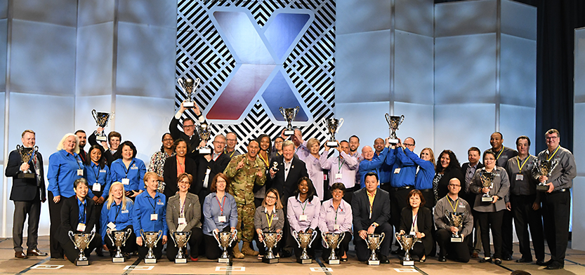 Main store managers and store managers hold up their trophies during their annual conference.