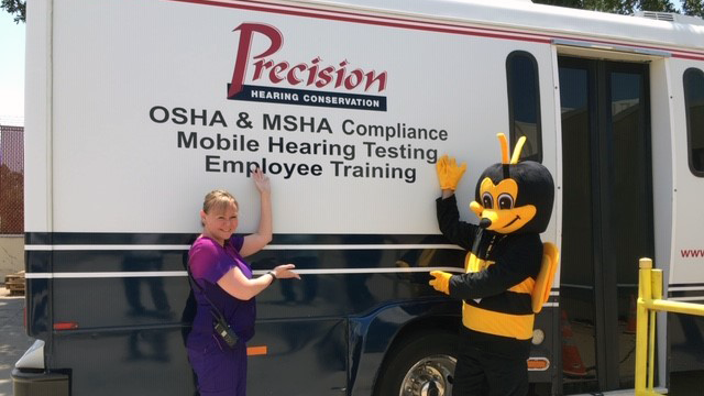 Lisa Monda, occupational health nurse at the Exchange’s Waco Distribution Center, and Buzz the Safety Bee show off the mobile hearing bus.