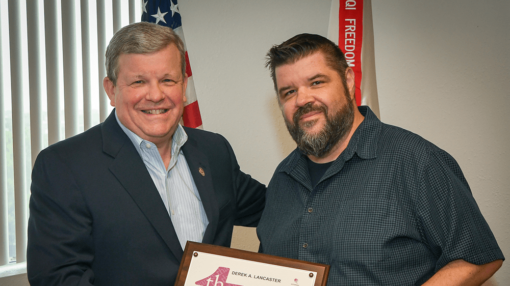 Director/CEO Tom Shull presents awards to Graphic Artist 
Derek Lancaster. was presented the new coin from Exchange Director/CEO Tom Shull on July 10.