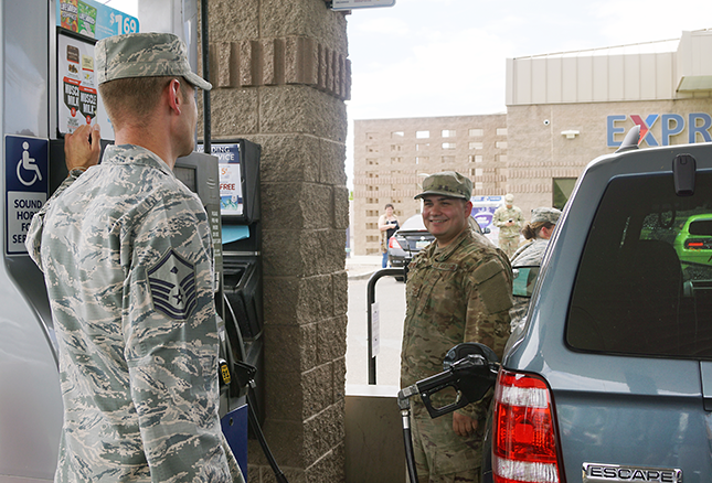 A members of the First Sergeants Council, left, pays for free gas. He even cleaned the vehicle's windshield.