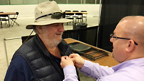 Exchange General Manager Brian Read pins a Vietnam Veteran lapel pin on the coat of a Veteran.