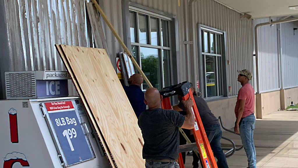 Workmen attach metal shutters to windows of the Camp Santiago Exchange in Puerto Rico to protect the building from storm damage.