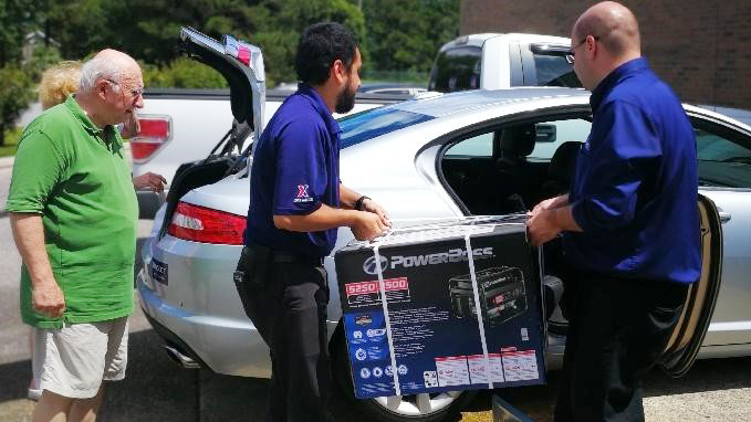 Associate Michael Chambers and Assistant Store Manager Christopher Camps helps load a power generator into a customer's vehicle.