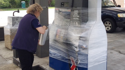 Shift Manager Marion Koenig wraps a gas pump in protective plastic at the Express before the store closes.