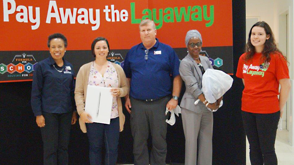 Left to right, Main Store Manager shopper Elaine Thomson, Operations Manager David Parker; shopper Bonita Jones, and Customer Service Associate Kayley-Ann Hanner celebrate the Exchange paying off the layaways. Thompson's MacBook and Jones' backpack and kids' clothing were paid off.