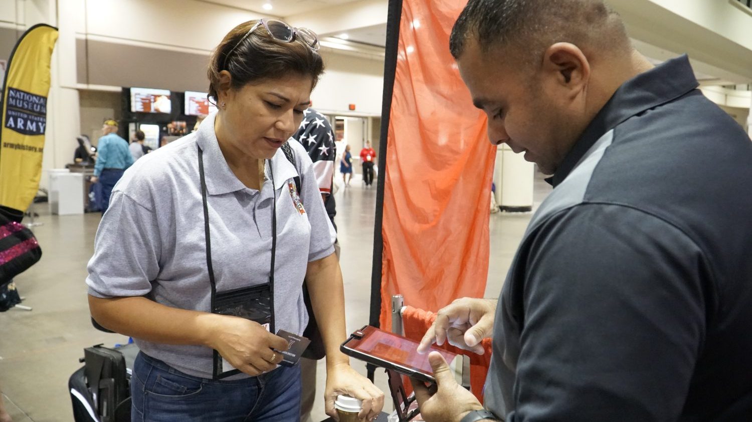 From left, Army Veteran Francis Cordero Medina learns how to sign up for tax-free shopping at ShopMyExchange.com with help from Exchange Veteran Service Organization/Military Service Organization Outreach Manager Jose Hernandez at the VFW Convention this summer. 