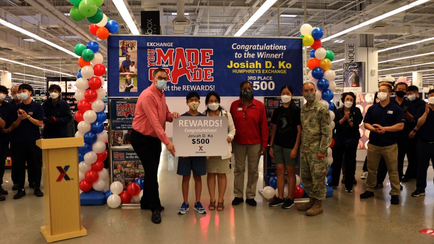 Josiah Ko's father, Maj. David Ko, chaplaincy resource manager for Headquarters, Headquarters Company, United States Army Garrison-Humphreys; his mother, Jenny; and his sister, Annabelle, join the Exchange’s Regional Vice President Scott Bonner and Humphreys Store Manager Debra Melton for the presentation of Josiah's $500 gift card.