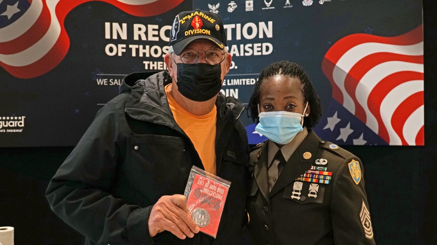 Don Collins (left), a retired Marine Master Sgt. and combat photographer, stands with Sgt. Maj. Lemakius Gardner (right), senior enlisted advisor for Exchange Europe/Southwest Asia/Africa Region after receiving a challenge coin in honor of Veterans Day Nov. 11 at the Kaiserslautern Military Community Exchange at Ramstein Air Base, Germany.