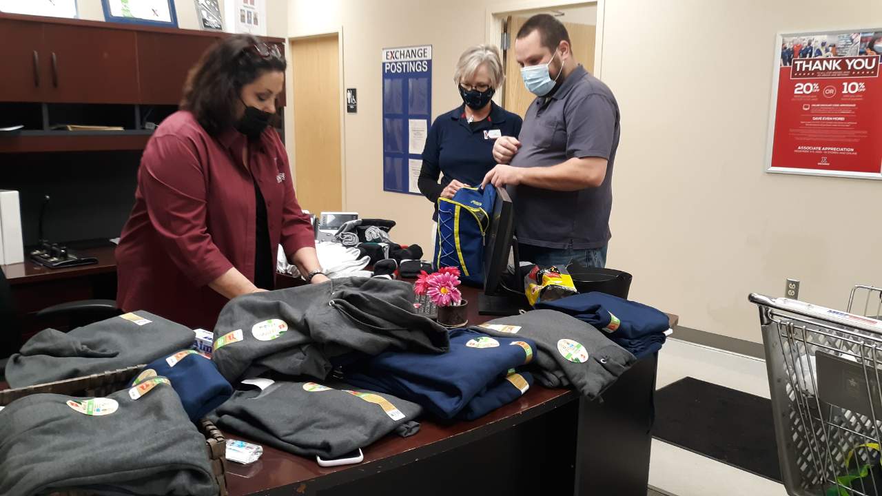 Wright-Patterson Main Store Manager Cynthia Gregg, left, and Military Store Manager Kim Dawes help the gift-card winner assemble items for homeless Veterans. The customer, a disabled Navy Veteran, also used his $1,000 prize to donate items to Toys for Tots.