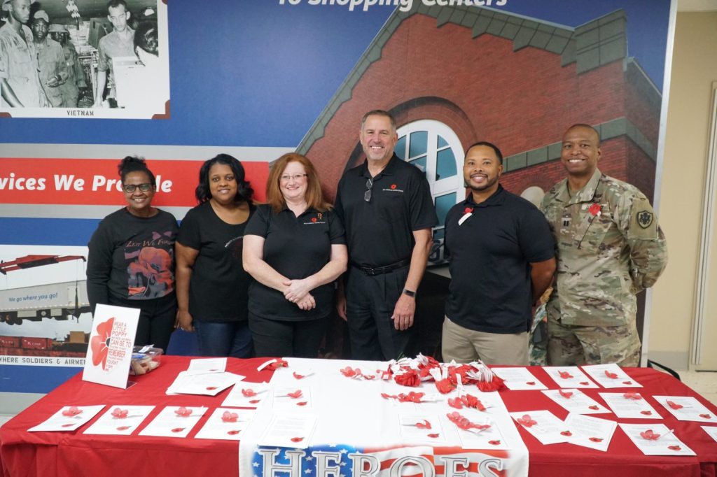 <b>Senior Business Systems Analyst Sandra Wicker; Business Program Specialist Shalandrea Smith; Vice President of Services, Health & Wellness & Telecom Denise Gumbert; Senior Vice President of Real Estate Mike Smietana; Vice President of Credit Operations Joseph Todd; and Transportation Officer Capt. Bradley Bush of HEROES with red poppies to hand out for National Poppy Day. Smietana and Gumbert are the group's executive champions.

Exchange associates arriving to headquarters on May 26 were presented with poppies in recognition of National Poppy Day (May 27).

Members of the HEROES Special Emphasis Program distributed the poppies, marking the third year the program has participated in National Poppy Day. HEROES recognizes the contributions and sacrifices of Exchange associates and retirees who are military Veterans, their spouses and family members.

The red poppy is a nationally recognized symbol of sacrifice worn by Americans since World War I to honor those who served and died for our country in all wars. It serves as a reminder to Americans of the sacrifices made by Veterans while