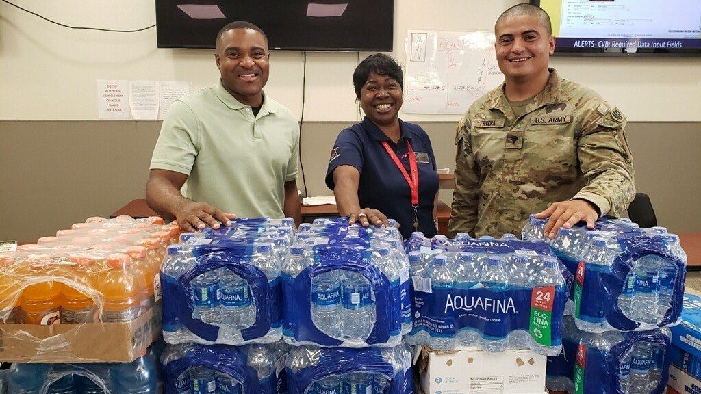 <b>Fort Bragg Exchange mail courier Andrea Moore with one of the water shipments. At left is an unidentified military police investigator. Ar right is 