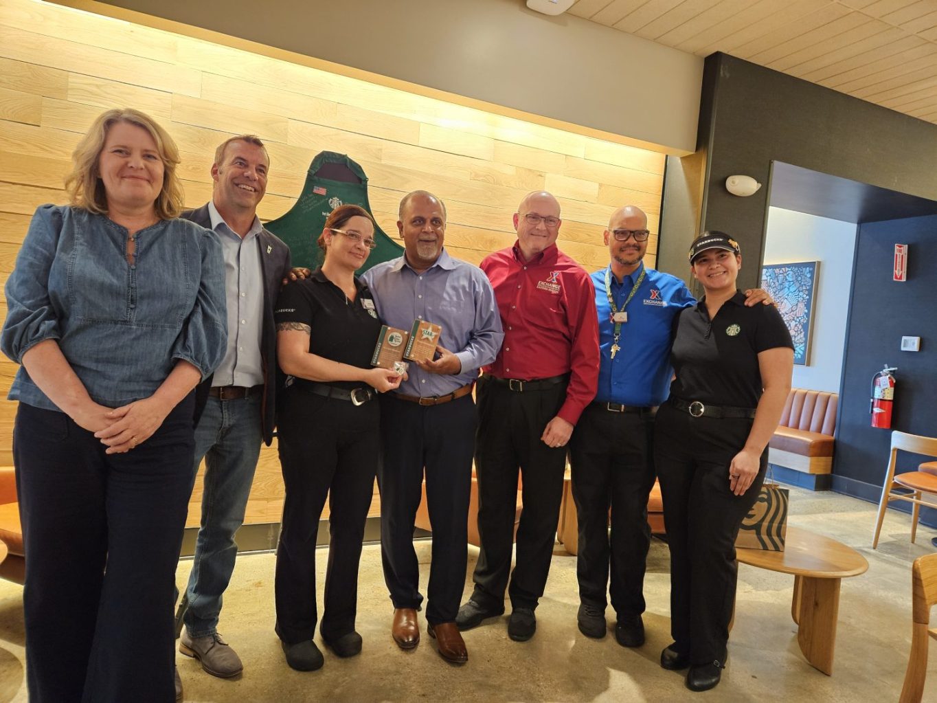 <b>Starbucks leaders honor Fort Liberty Exchange leaders for their contributions to the success of the Starbucks location. From left: Regional Director Starbucks Sarah Zabrosky; Starbucks License District Manager Ted Brown; Exchange Facility Manager North Post Starbucks Karolyn Madera; Exchange General Manager Thomas "TK" Kuttamperoor; Regional Vice President, Central Eastern Chris Holifield; Mini Mall Starbucks Store Manager Caroll Poston; and Fort Liberty South Post Starbucks Store manager Francelis Fuster. </b>