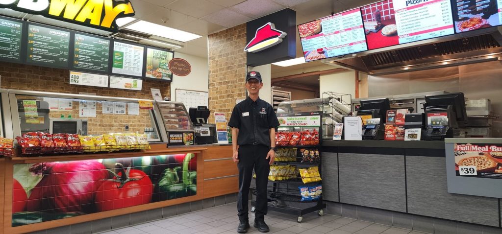 Dragon Hill Lodge Food Court Manager Yi, Yong-pom in front of the Subway and Pizza Hut counters.