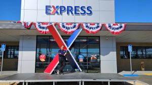 Fort Irwin Visual Merchandiser Ricardo Orfin with a sculpture of the Exchange brand he made for an Express convenience store grand opening.