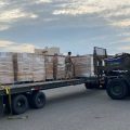 Pictured: A forklift and stacks of boxes on a truck-trailer bed.