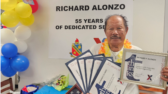 Presidio of Monterey Exchange associate Richard Alonzo at his 55th work anniversary celebration, holding years-of-service certificiates.