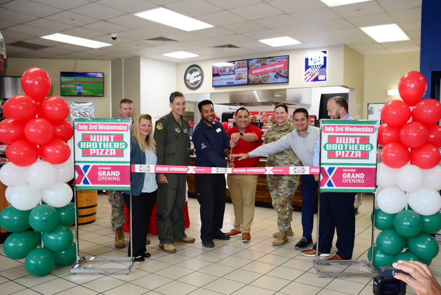 Exchange, installation and Hunt Brothers Pizza leaders prepare to cut the ribbon at the new Hunt Brothers at Yokota Air Base.