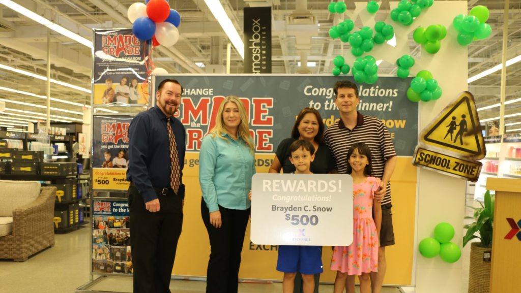 Brayden Snow accepts third place in the Exchange's You Made the Grade contest, accompanied by his parents and sister. Also pictured are the USAG Humphreys Exchange general manager and store manager.