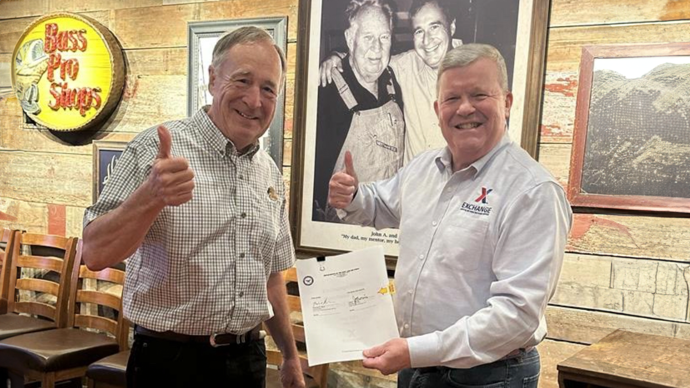 Exchange Director/CEO Tom Shull and Bass Pro Shops founder and noted conservationist Johnny Morris display the agreement to bring Bass Pro Shops to the Exchange