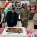 Four people cutting a cake at the Zama Express Hunt Brothers Pizza grand opening.