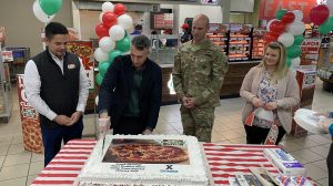 Four people cutting a cake at the Zama Express Hunt Brothers Pizza grand opening.